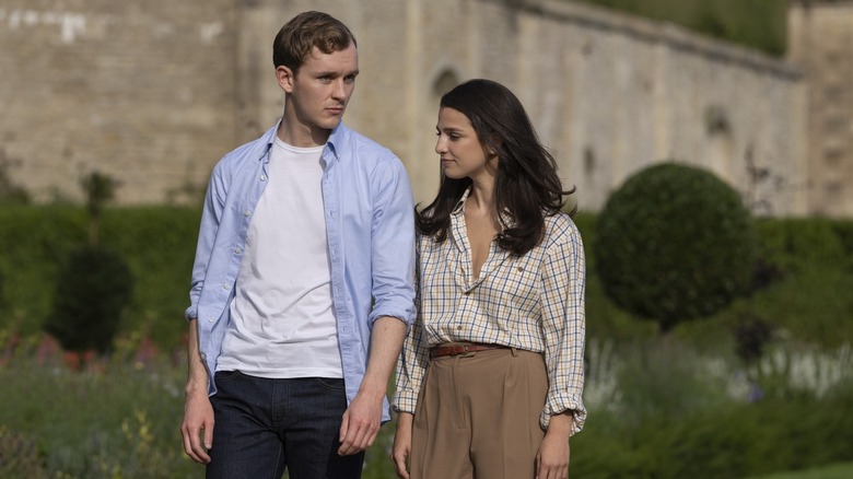 Robert and Yasmin walking outside of a large stone house on Industry