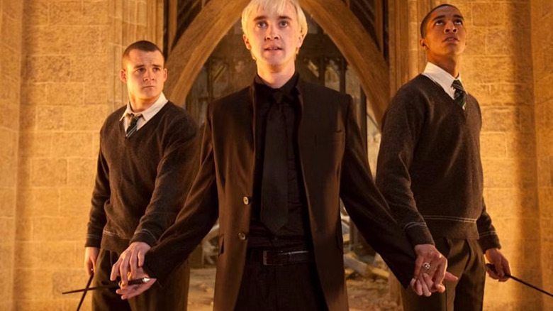 Draco Malfoy, flanked by two flunkies holding his hands, all of them holding wands.