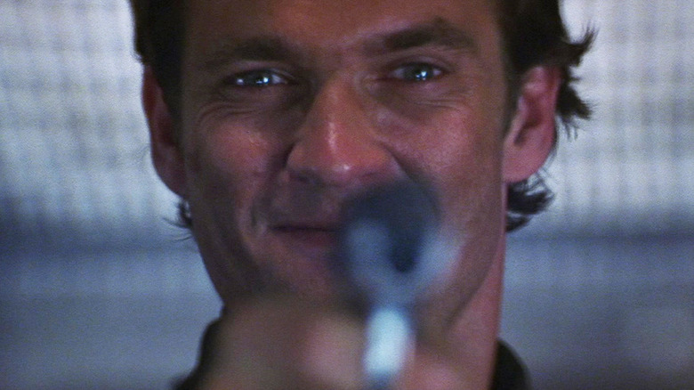 Dougray Scott como Sean Ambrose apuntando con un arma a la cámara en Misión: Imposible II