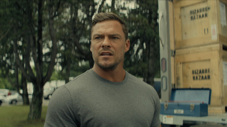 Alan Ritchson's Jack Reacher stands in front of a truck