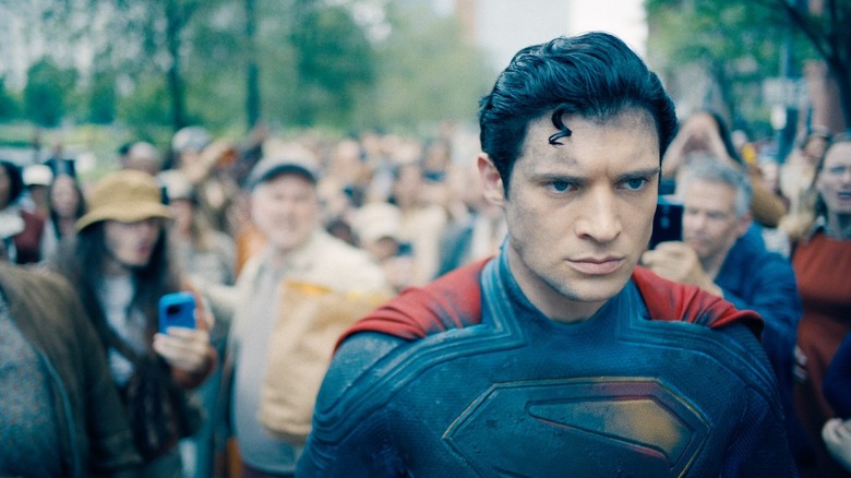 David Corenswet as Superman walking among a crowd and looking disheveled in a scene from Superman