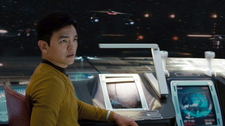 Sulu, at the helm of the U.S.S. Enterprise, a viewscreen behind him in Star Trek