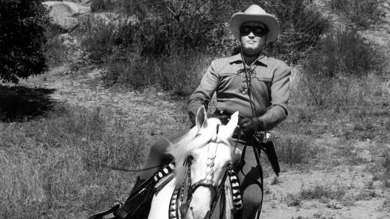 The Lone Ranger on horseback, riding through the hills