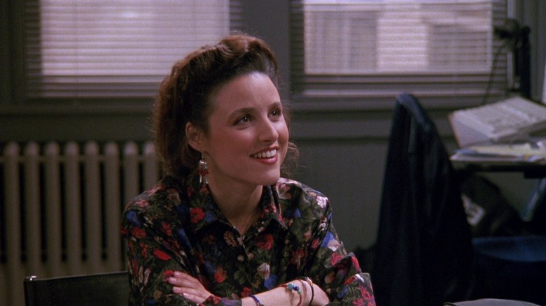 Elaine Benes, smiling at a desk.