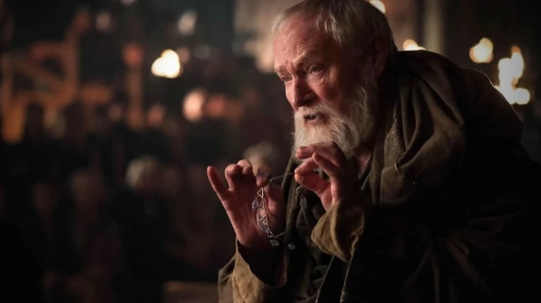 Julian Glover's Maester Pycelle holds up a necklace in Game of Thrones