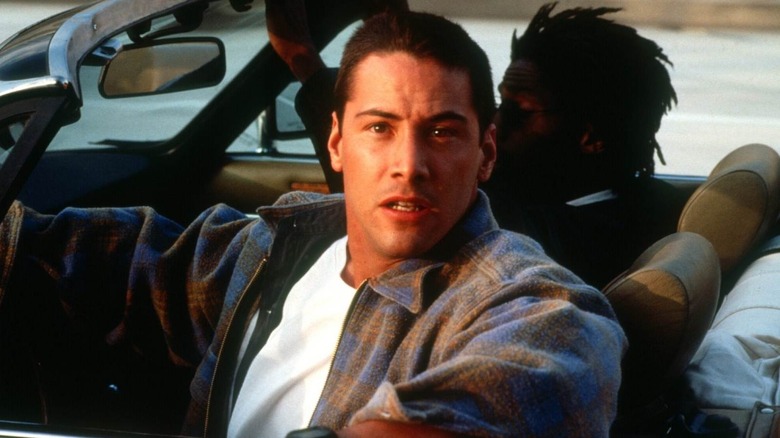 Keanu Reeves as Jack looking behind him in car in Speed