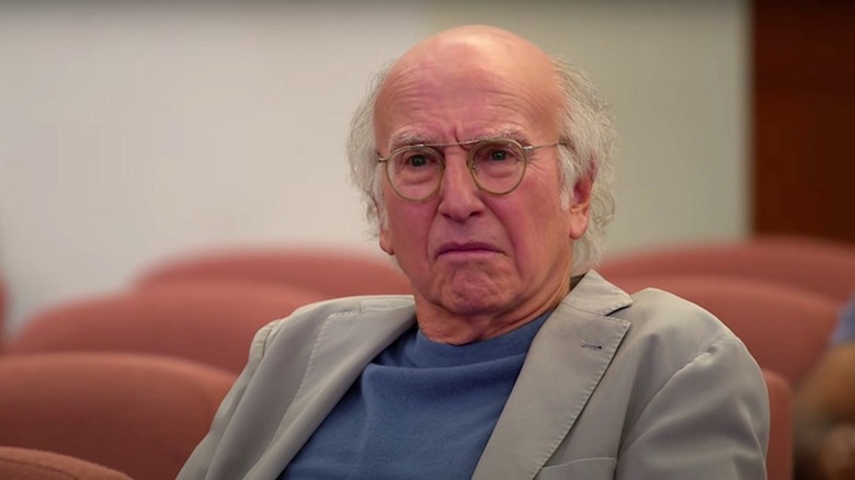 Larry David faz um rosto azedo em uma sala de exibição em Curb Your Enthusiasm