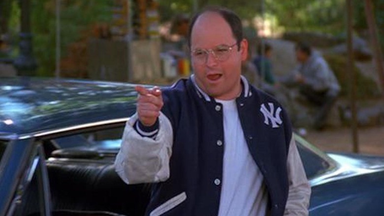 Jason Alexander makes a finger pistol wearing a Yankees jacket as George Costanza in Seinfeld