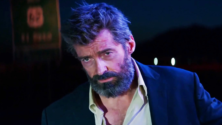 Hugh Jackman's Logan looks incredulous as he stands in a suit jacket and open shirt in Logan