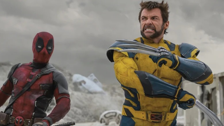 Ryan Reynolds' Wade Wilson looks on while Hugh Jackman's Logan/Wolverine stands in a fighting pose, claws out, in Deadpool & Wolverine