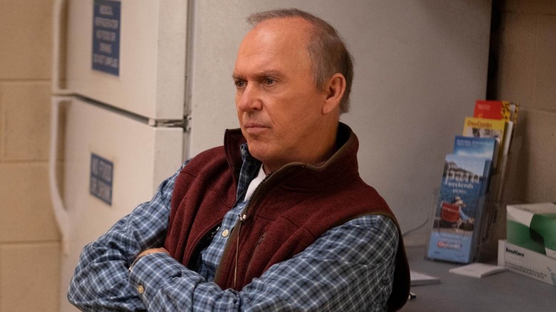 Michael Keaton as Samuel Finnix in Dopesick, crossing his arms and looking at something off-screen