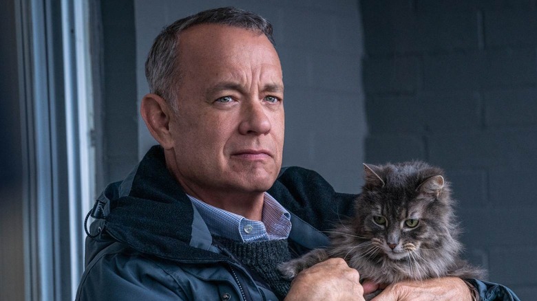 Tom Hanks as Otto holding a cat and frowning a little in A Man Called Otto