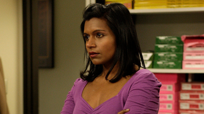 Mindy Kaling standing by Andy's desk with her arms crossed in The Office