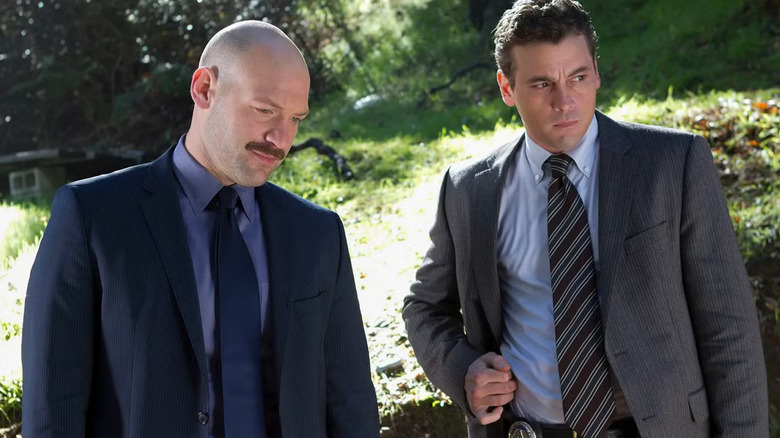 Detectives TJ Jeruszalski and Rex Winters, looking at something in a park on Law & Order: LA