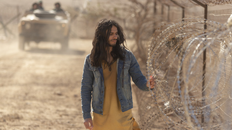 al-Masih putting his hand against a barb wire fence in Messiah