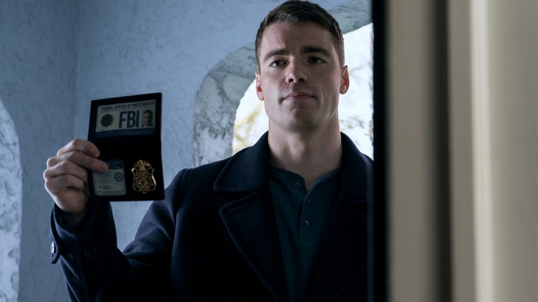 Gabriel Basso's Peter holds up an FBI ID badge in The Night Agent