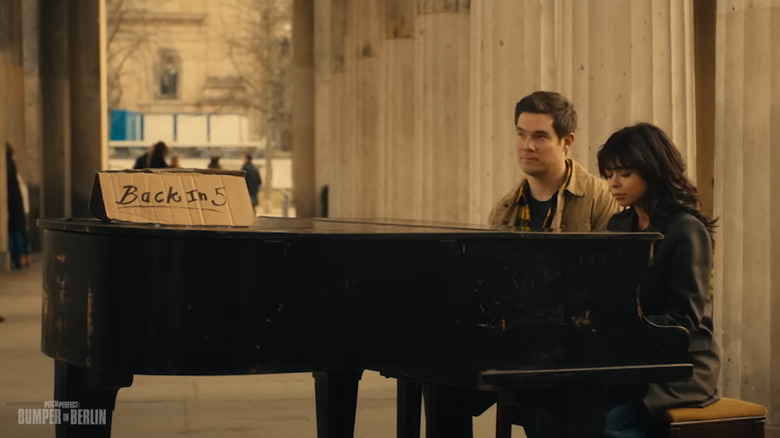 Adam DeVine as Bumper and Sarah Hyland as Heidi sitting at a piano on Pitch Perfect: Bumper in Berlin