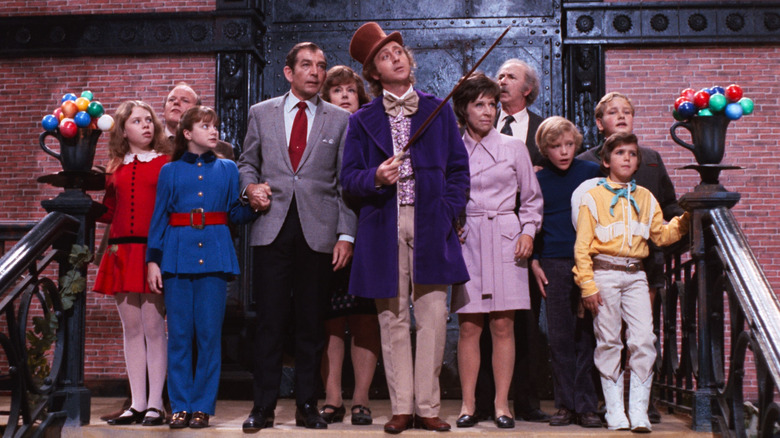 Willi Wonka, surrounded by children and their parents, in a gesture with a stick, a scene from Willi Wonka and the chocolate factory.