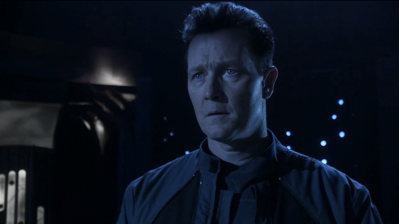 Robert Patrick's Colonel Marshall Sumner is lit by blue light as he stands against a black background in Stargate Atlantis