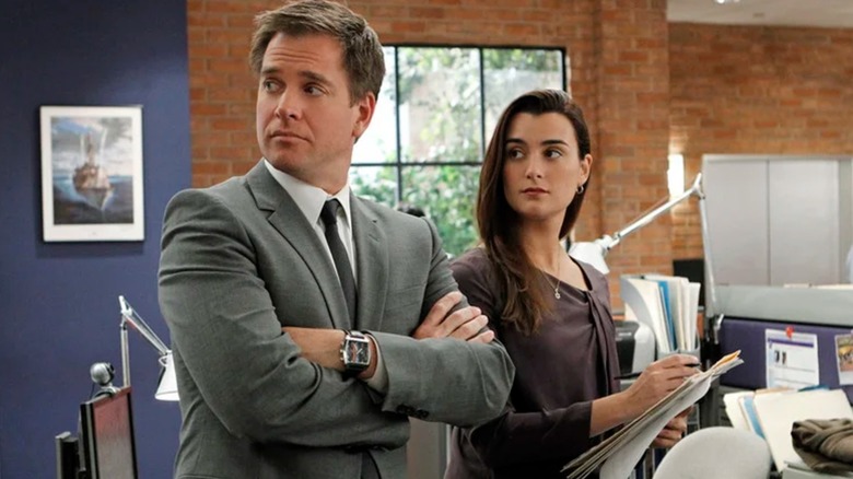 Tony e Cote de Pablo, de Michael Weatherly, que estão segurando a papelada, olham fora da tela à direita no NCIS