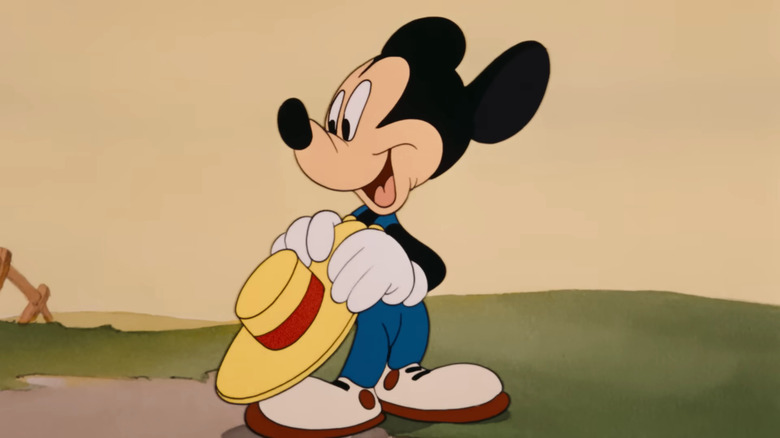 Mickey Mouse wearing gloves, holding a hat