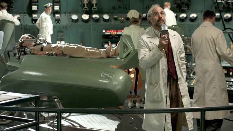 Dr. Erskine in the middle of a high-tech lab, surrounded by technicians. A pre-transformation Captain America is on a gurney behind him.