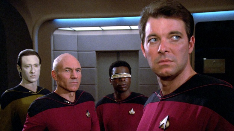 Brett Spiner as Data, Patrick Stewart as Picard, LeVar Burton as Geordi, and Jonathan Frakes as Riker standing together in Star Trek: The Next Generation