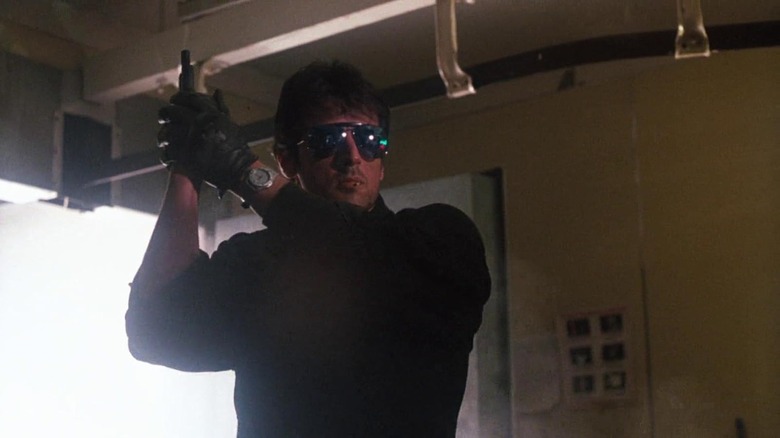 Marion Cobretti, wearing sunglasses, holding a pistol in a vertical position