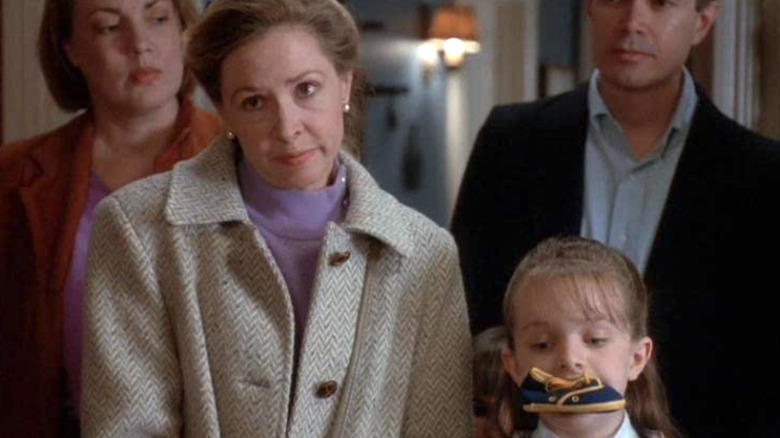 The central family from Picket Fences. A young girl has a miniature shoe in her mouth.