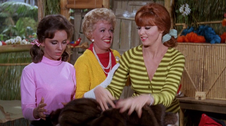 Mary Ann, Mrs. Howell, and Ginger, piling clothes on a table. A scene from Gilligan's Island.