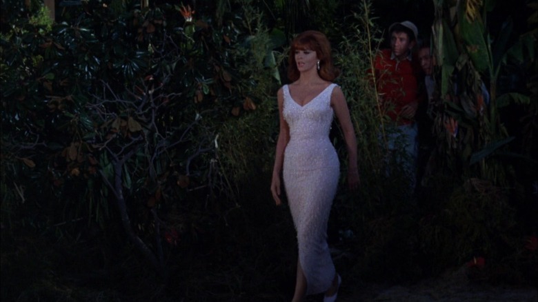 Ginger, in a long white gown, walking along the beach at night. She's fabulous. Gilligan and the Skipper peek out from behind a bush. From Gilligan's Island.