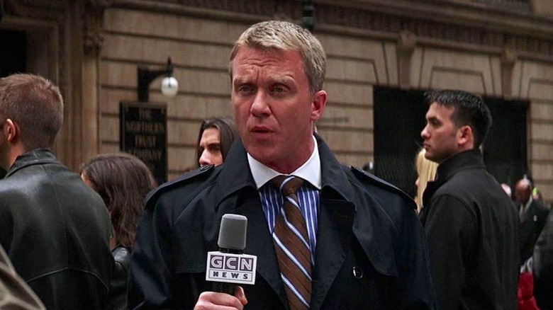 Mike Engel holding a microphone in The Dark Knight