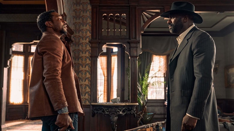 Idris Elba and Jonathan Majors standing face to face in The Harder They Fall