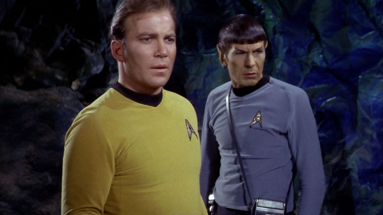 Captain Kirk and Spock in a cave, looking at something concerning in Star Trek