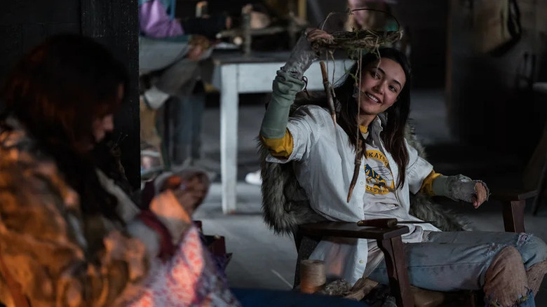 Mari playing with a wooden string toy as Lottie sits near her on Yellowjackets