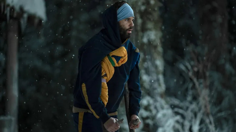 Coach Ben Scott standing on crutches while it snows around him on Yellowjackets