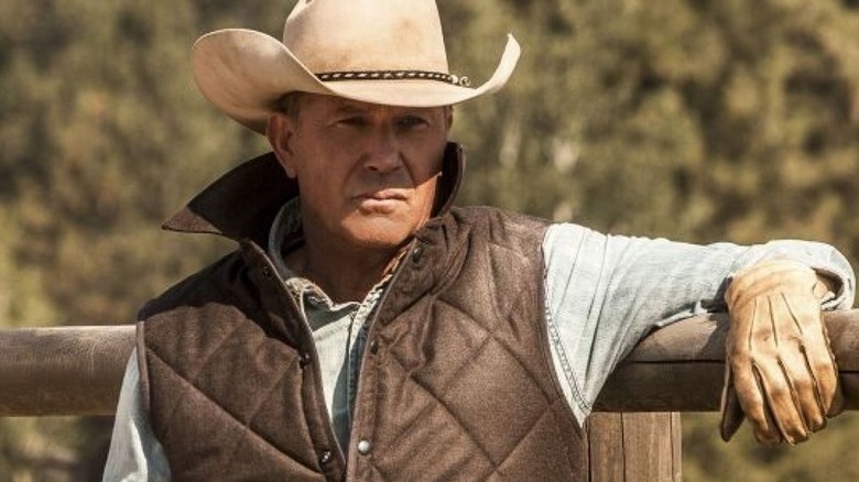 John Dutton leaning against a fence on Yellowstone