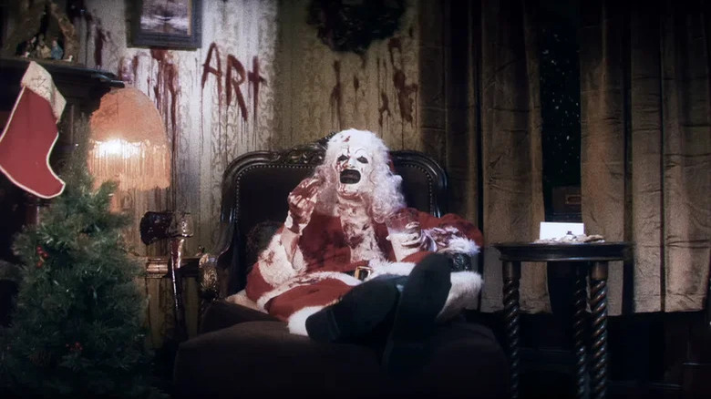 Art o palhaço comendo biscoitos e bebendo leite como Papai Noel em Terrifier 3