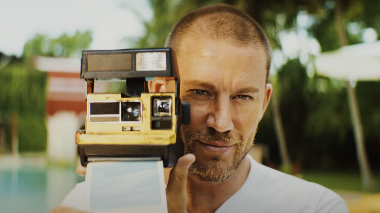 Channing Tatum's King Slater holding a Polaroid camera blinking twice