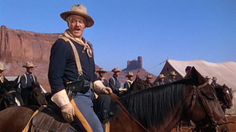 John Wayne as Captain Nathan Brittles on a horse in the desert with his troops in She Wore a Yellow Ribbon